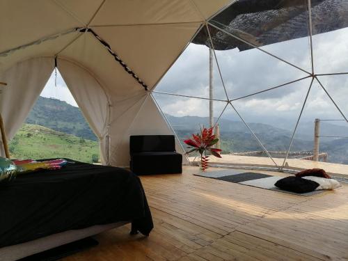 a bedroom with a tent with a view of a mountain at Domo Glamping Kalpavriksha - Jostcolombia in La Vega