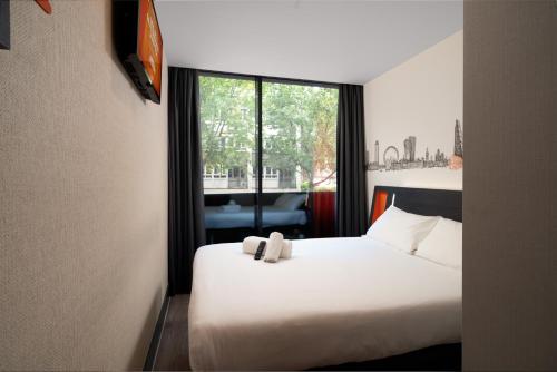 una camera d'albergo con un letto bianco e una finestra di easyHotel Oxford a Oxford