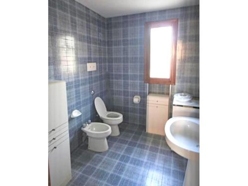 ein blau gefliestes Bad mit WC und Waschbecken in der Unterkunft BA - Maestrale- in Lignano Sabbiadoro