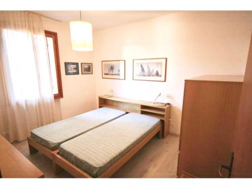 Schlafzimmer mit einem Bett, einem Schreibtisch und einem Fenster in der Unterkunft BA - Maestrale- in Lignano Sabbiadoro