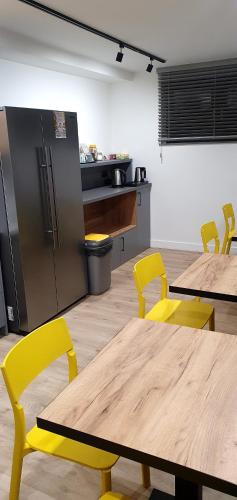 a kitchen with tables and yellow chairs and a refrigerator at VILLA 17 Noclegi in Płock