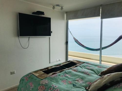 a bedroom with a bed with a flat screen tv on the wall at La Choza VIP Turquesa en La Serena, frente al mar in Coquimbo
