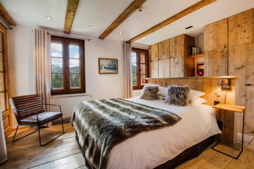 une chambre avec un grand lit et une chaise dans l'établissement Chalet Bizet - A touch of Parisian design in the Alps, à Montriond
