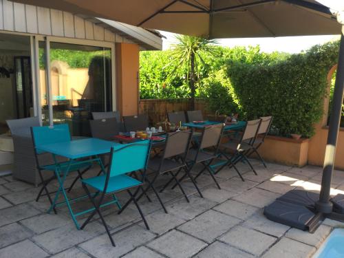 Una mesa y sillas azules bajo una sombrilla en un patio. en Domaine Des Deux Rivières, en Meilhan-sur-Garonne