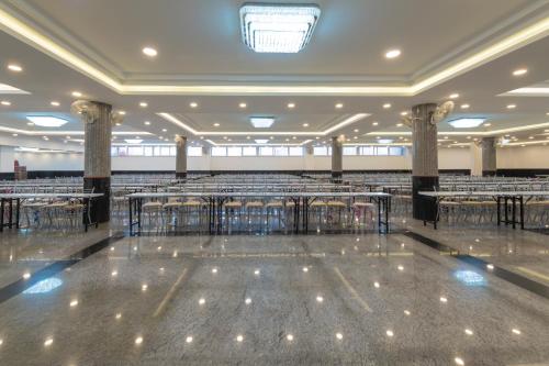 a large banquet hall with tables and chairs at AARYA MANSION V One Hotel in Hassan