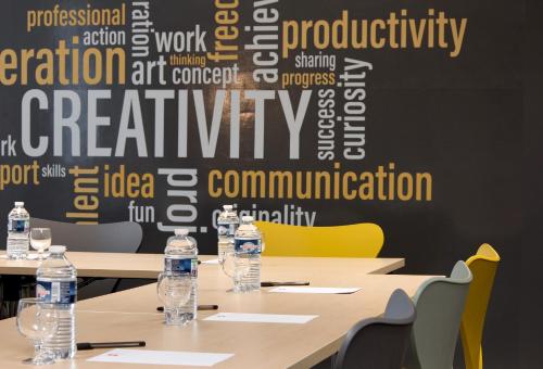 a conference room with tables and bottles of water at ibis budget Clermont Ferrand Nord Riom in Riom