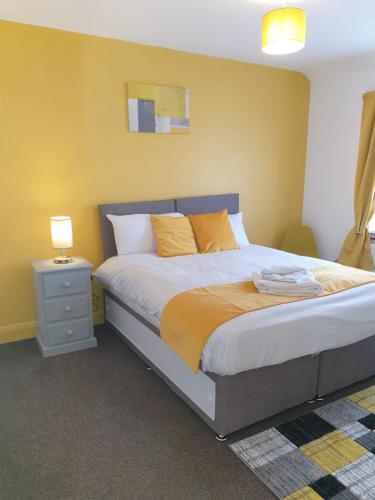 a bedroom with a large bed with orange pillows at Large 4bed house up to 6 beds parking Slough Train Station in Slough