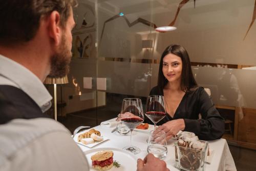 a man and woman sitting at a table with wine glasses at Hotel Chalet Del Brenta in Madonna di Campiglio
