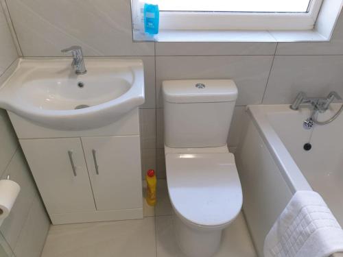 La petite salle de bains est pourvue de toilettes et d'un lavabo. dans l'établissement Large 4bed house up to 7beds parking Slough Train Station, à Slough