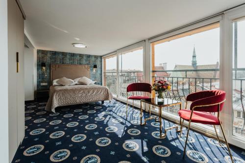 a bedroom with a bed and two chairs on a balcony at Hotel Jan in Kraków