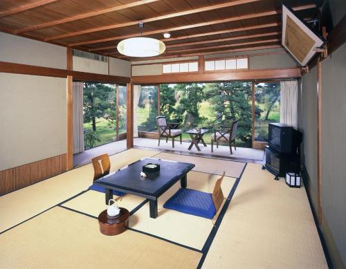 a living room with a table and chairs and a television at Seikiro Ryokan Historical Museum Hotel in Miyazu