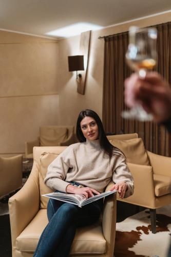 a woman sitting in a chair with a book at Hotel Chalet Del Brenta in Madonna di Campiglio