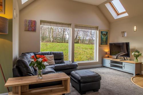 a living room with a leather couch and a tv at Highland Annexe, Munlochy, The Black Isle in Munlochy