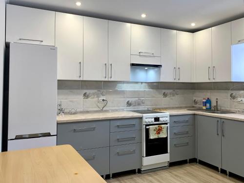 a kitchen with white cabinets and a wooden table at UNDERHILLs house in Yaremche