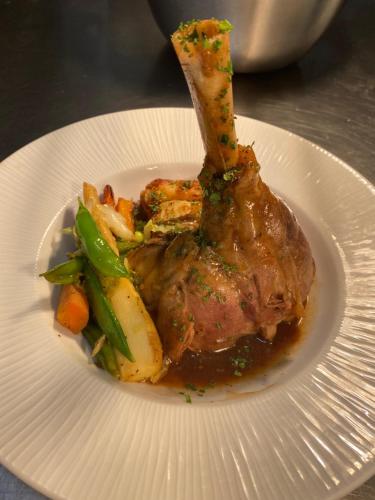 a white plate with a piece of meat and vegetables at Waveney House Hotel in Beccles