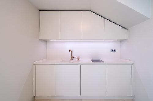 a kitchen with white cabinets and a sink at Barreirinha Suite Top Floor by Holiday Rental Madeira in Funchal