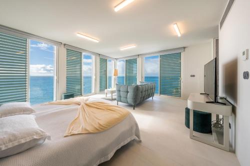 a bedroom with a bed and a room with the ocean at Barreirinha Suite Top Floor by Holiday Rental Madeira in Funchal