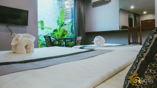 a row of four beds with towel animals on them at Hotel Five.S in Kampot