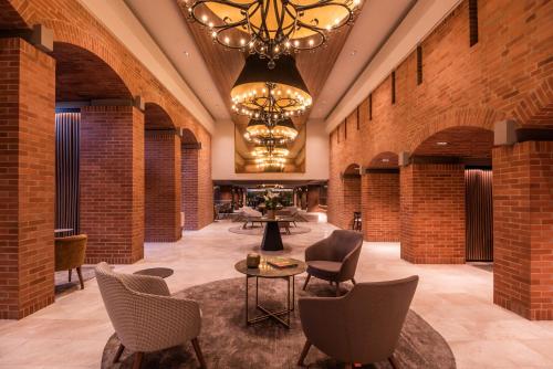 a lobby with brick walls and chairs and a chandelier at Estelar Apartamentos Bogotá - La Fontana in Bogotá