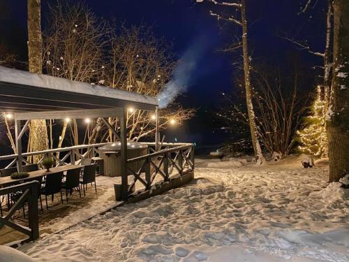 a table and chairs in the snow at night at Mošķu Pirts meža māja in Turaida