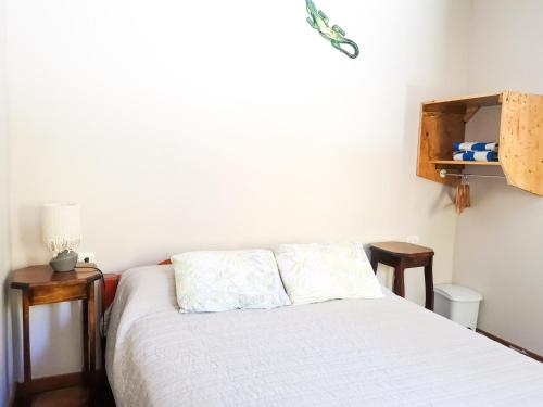 a bedroom with a white bed with two wooden tables at Casita happy feet and tours corcovado in Drake