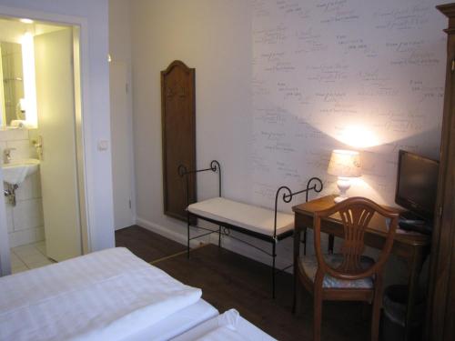 a bedroom with a bed and a desk and a chair at Hotel Willert in Wismar