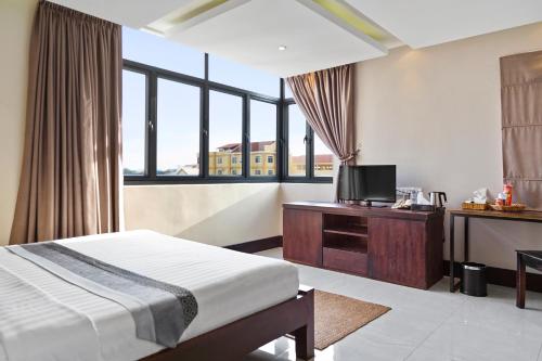 a hotel room with a bed and a tv and window at Hotel Five.S in Kampot