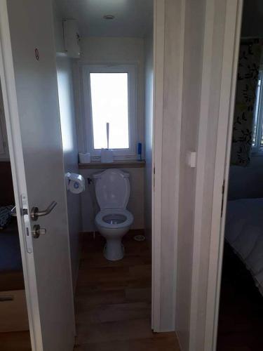 een badkamer met een toilet en een raam bij Luxueuze stacaravan in Bredene met eigen terras en tuintje (425) in Bredene