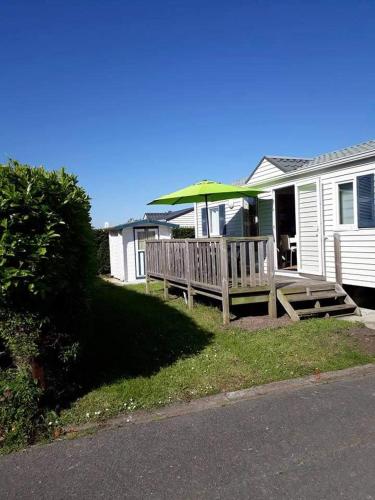 a wooden bench with an umbrella in front of a house at Luxueuze stacaravan in Bredene met eigen terras en tuintje (425) in Bredene