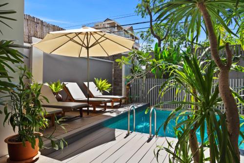 a patio with chairs and an umbrella next to a pool at Hotel Five.S in Kampot