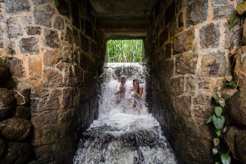 two people standing in a waterfall in a stone wall at Canto das Águas Atibaia in Atibaia