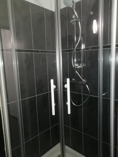 La salle de bains est pourvue d'une douche et de carrelage noir. dans l'établissement FLOREVA 43 Proche plage et thalasso, à Concarneau