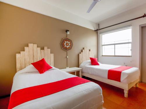 a bedroom with two beds with red and white sheets at Hotel Allende 104 in Chihuahua
