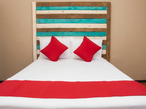 een bed met rode kussens en een houten hoofdeinde bij Hotel Allende 104 in Chihuahua