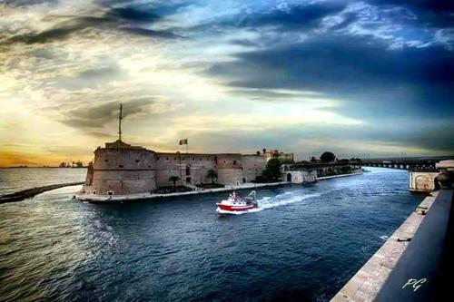 a small boat in the water near a castle at Casa Principe Taranto "Intero appartamento" in Taranto
