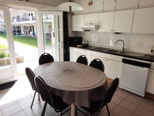 uma cozinha com mesa e cadeiras e uma cozinha com armários brancos em De Haan - Dahlia 007 em De Haan