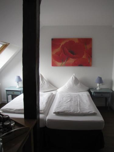 a bedroom with two beds and a painting on the wall at Hotel Willert in Wismar