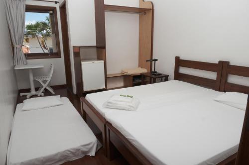two beds in a room with a window at Pousada Vista da Pedra Atibaia in Atibaia
