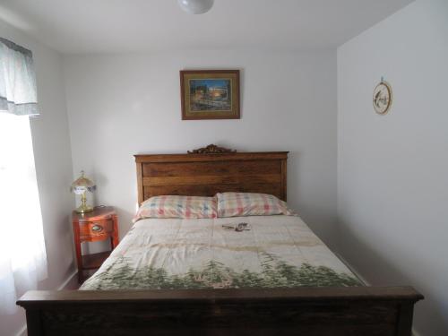 a bed in a white room with a wooden headboard at Fishing Creek Lodge at Ricketts in Benton