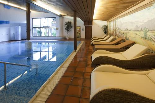 une piscine avec des chaises longues et un tableau mural dans l'établissement Sporthotel Wilder Kaiser, à Oberaudorf