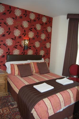 a bedroom with a bed with a red wall at The Trafford Hotel in Blackpool