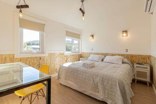 1 dormitorio con cama y mesa de cristal en Dolce Vita - Alojamiento Histórico, en Puerto Varas