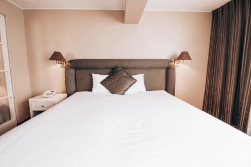 a bedroom with a large white bed and a phone at Suites del Bosque Hotel in Lima