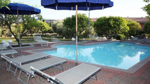 a large swimming pool with chairs and an umbrella at House and Apts. in Porto Azzurro 23632 in Porto Azzurro