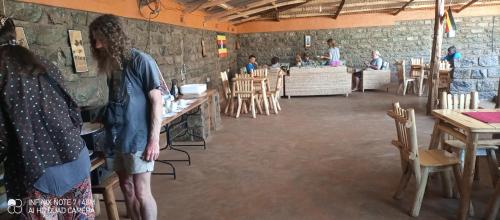 un uomo in piedi in una stanza con tavoli e sedie di Sipi Coffee Lodge a Kapchorwa