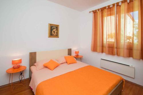 a bedroom with a bed with orange sheets and two lamps at Apartment in Vrbnik/Insel Krk 36842 in Vrbnik