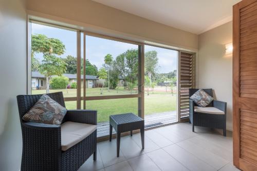 a screened porch with chairs and a table and windows at Copthorne Hotel & Resort Bay Of Islands in Paihia