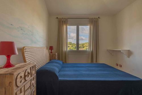 バージャ・サルディニアにあるHoliday home in Baja Sardinia 30356の青いベッドと窓のある寝室