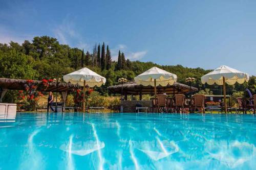 una grande piscina con ombrelloni, tavoli e sedie di Apartment in Capolona/Toskana 23622 a Capolona