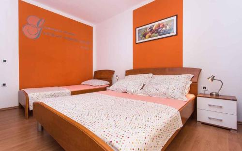 sypialnia z 2 łóżkami i pomarańczową ścianą w obiekcie Apartments in Vrbnik/Insel Krk 36005 w mieście Vrbnik